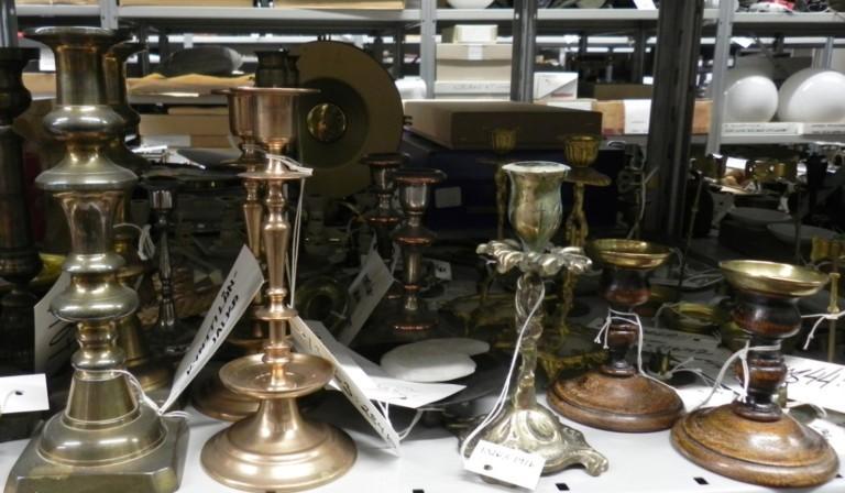 Messinkisiä kynttilänjalkoja hyllyllä.