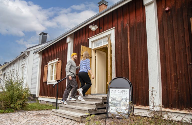 Kaksi henkilöä astumassa museorakennukseen.