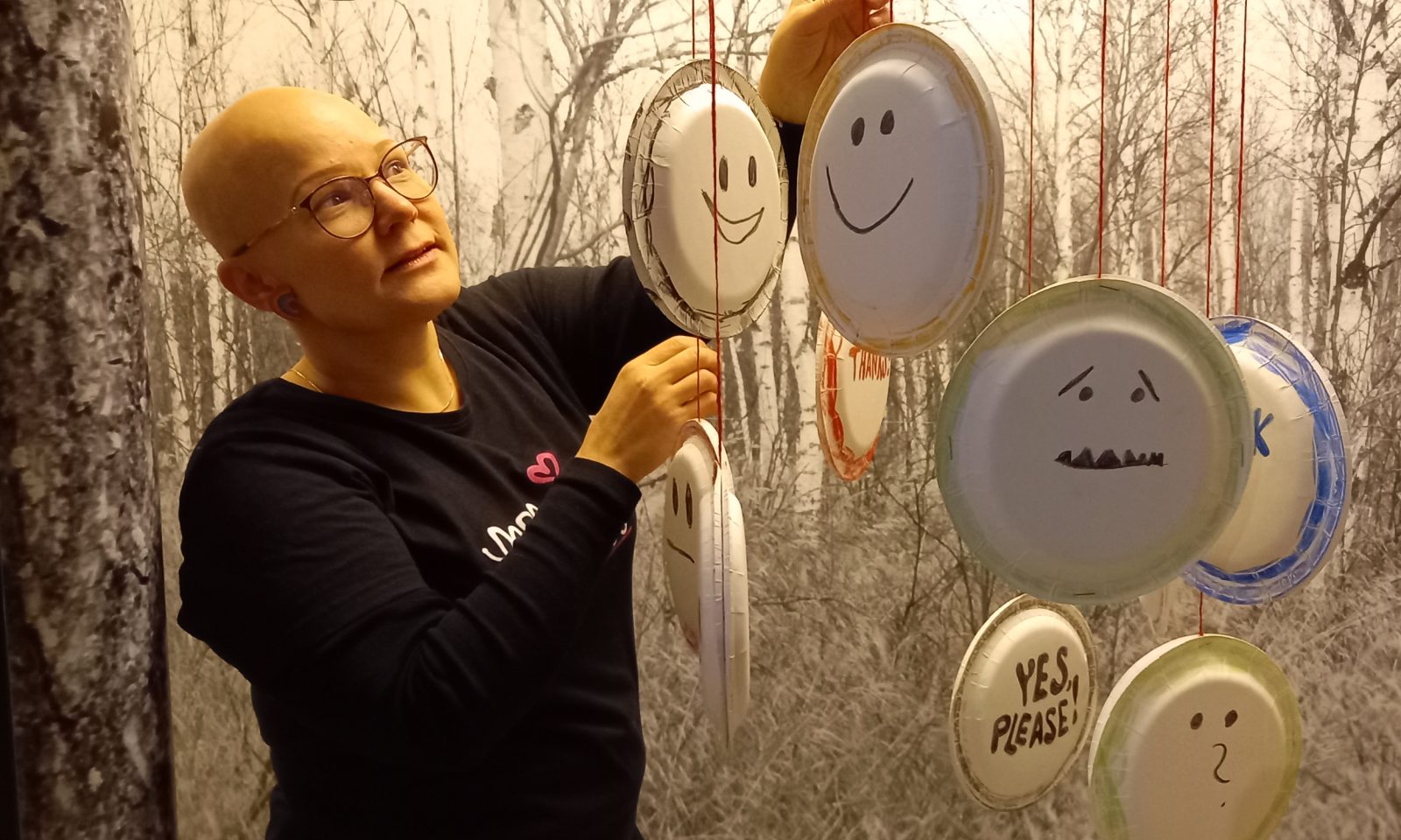 Nainen ripustamassa taidetta.