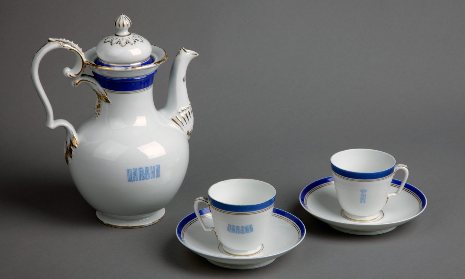 Posliininen kahvikannu ja kaksi kuppiparia.