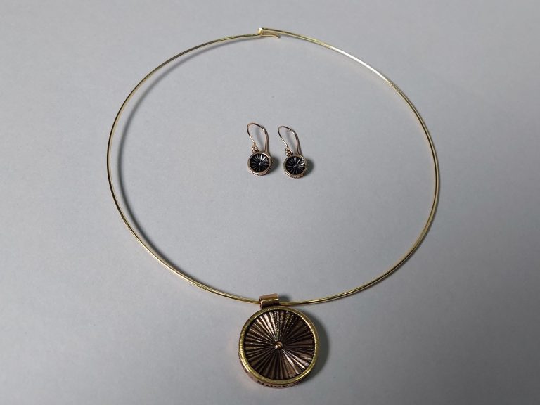 Pronssinen kaulapanta ja korvakorupari. Molemmissa pyöreä riipus.