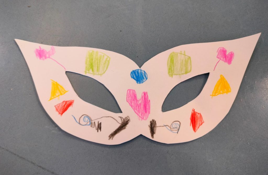 Paperista askarreltu maski silmille. Maski on koristeltu erivärisillä yksityiskohdilla.