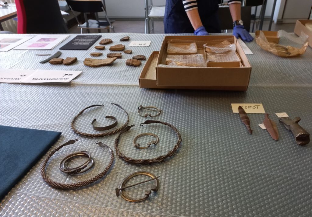 Pöydällä pieniä museoesineitä kuplamuodin päällä.