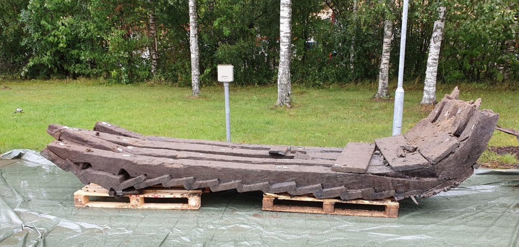 Puinen laivan osa lavojen ja pressun päällä.