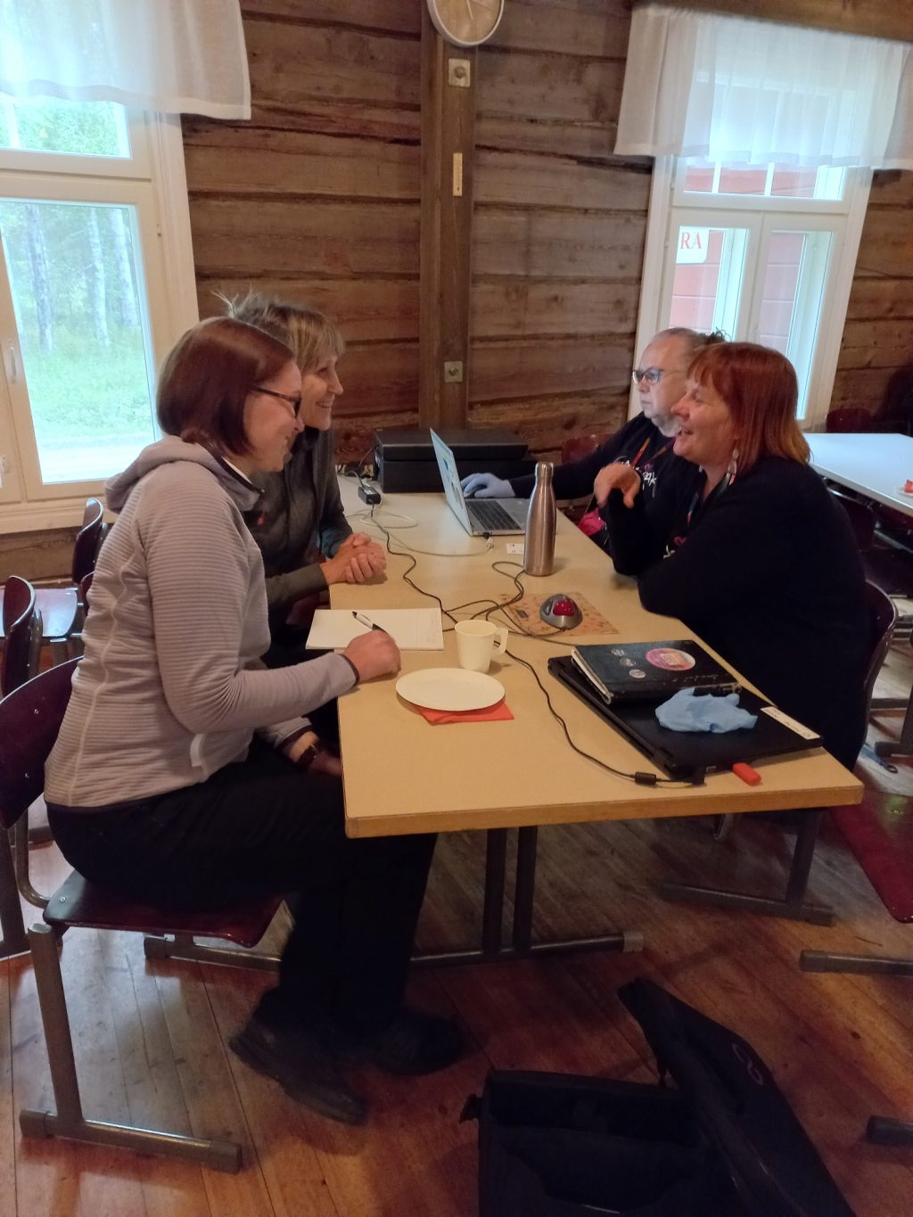 Neljä naista istuu vaaleapuisen pöydän ääressä.