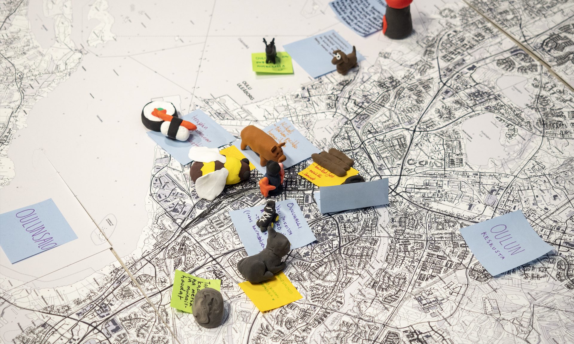 Muistilappuja ja pienesineita Oulun kartan päällä.