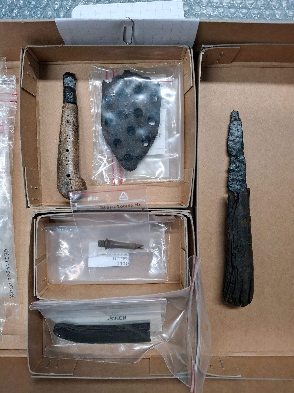 Eri muotoisia pieniä esineitä laatikossa ja pienissä muovipusseissa.