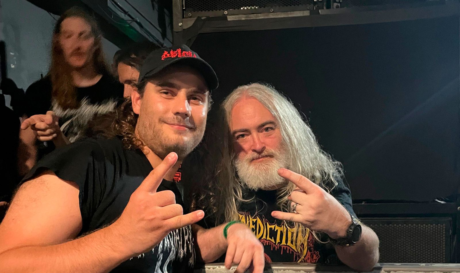 Kaksi hevimiestä poseeraa kameralle ja näyttä sormillaan hevimusiikkiin liitettävää yleistä käsimerkkiä.