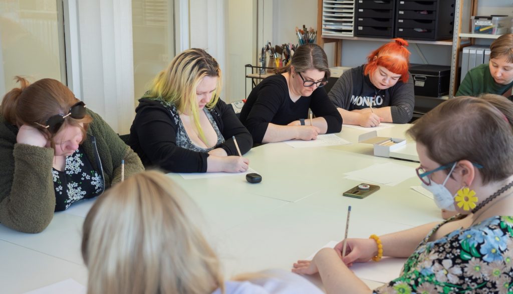 Ihmisiä pöydän ääressä kirjoittamassa papereille mietteliäinä.