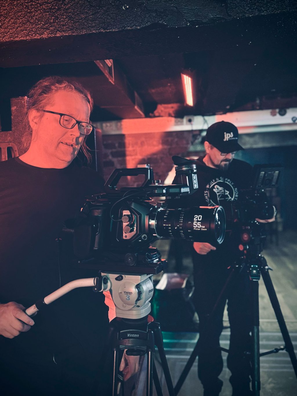 kaksi henkilö videohommissa hämyisässä ympäristössä.