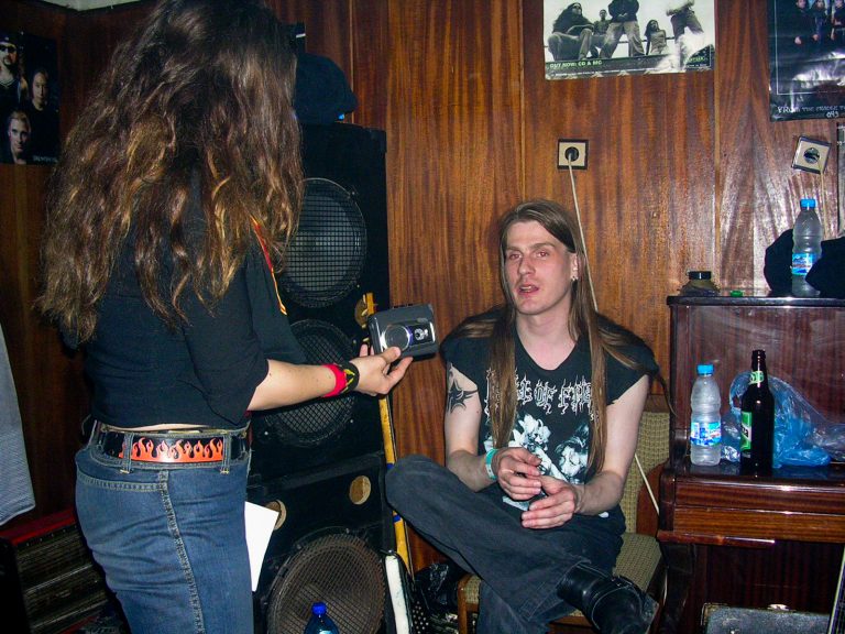 Riku Hopeakoski istuu puhumassa haastattelijan seisoessa nauhoittamassa keskustelua.