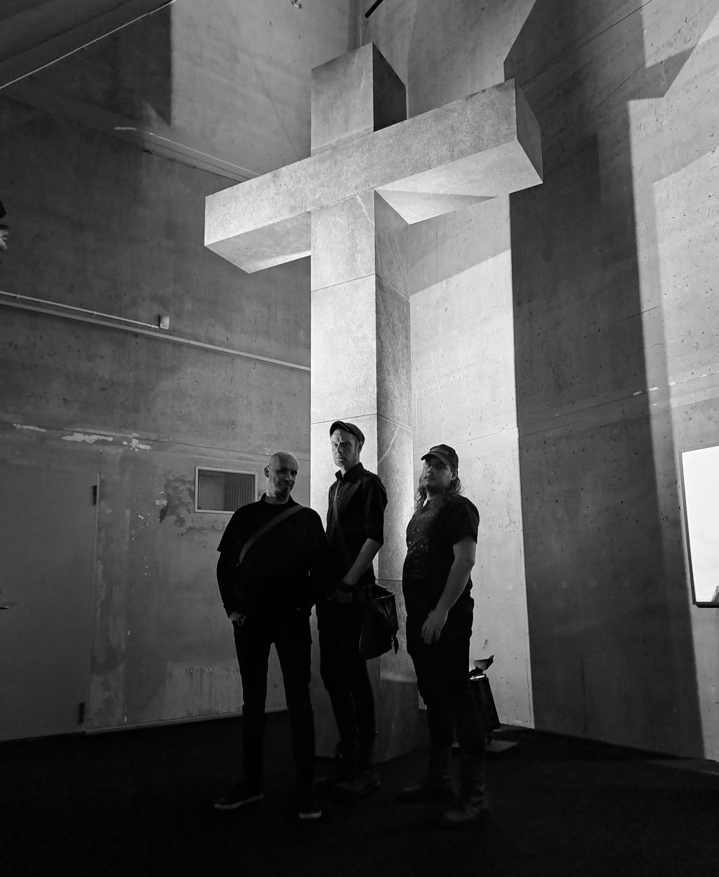 Kolme henkilöä seisoo suuren ristin alla.