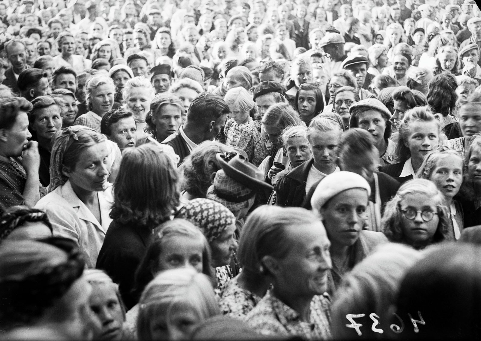 A black-and-white photograph of a large group of people, taken from above their heads.