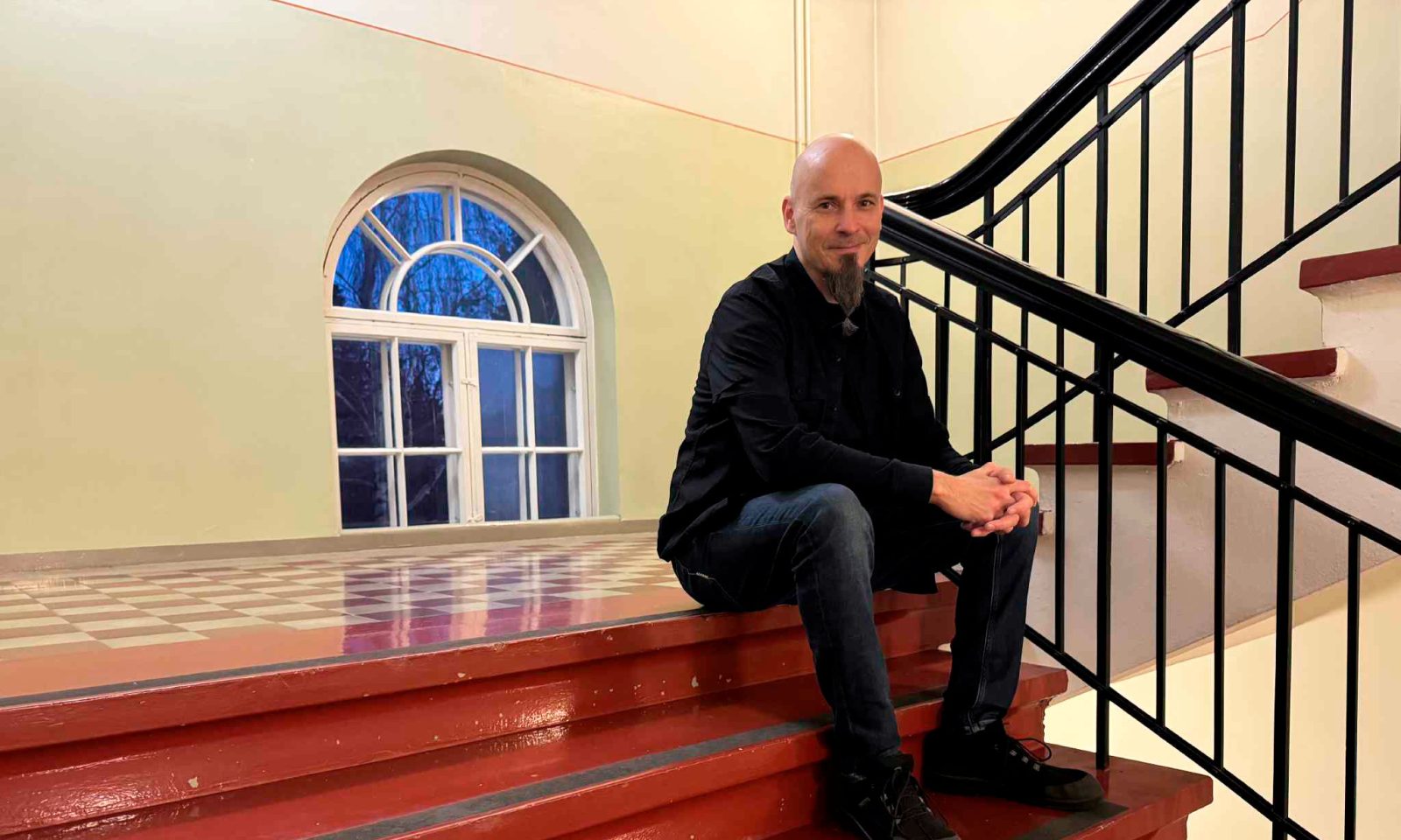 Henkilö istuu rappukäytävän portailla.