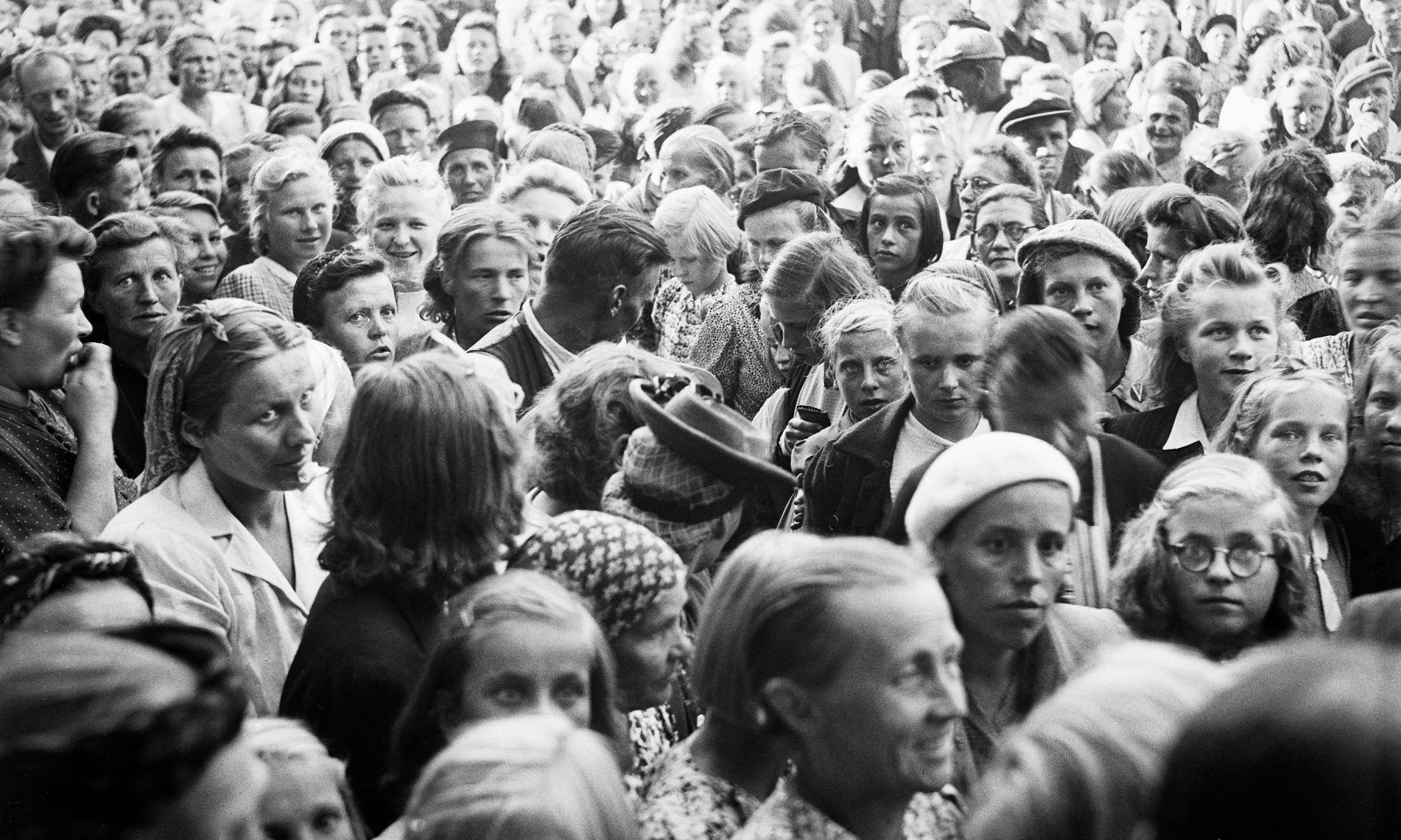 Mustavalkoinen kuva isosta joukosta henkilöitä, kuvattu ylhäältä päiden päältä.
