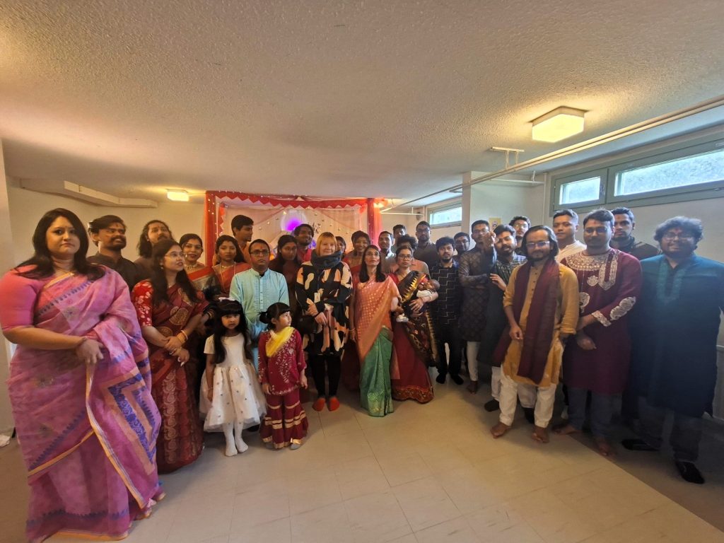 Ihmisiä kokoontuneena ryhmäkuvaan. Useilla päällään intialaiset juhla-asut.