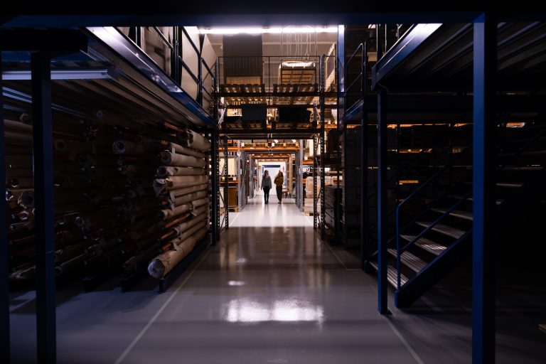 Varastokäytävää, jonka molemmilla puolilla korkeita hyllyjä täynnä museoesineitä.