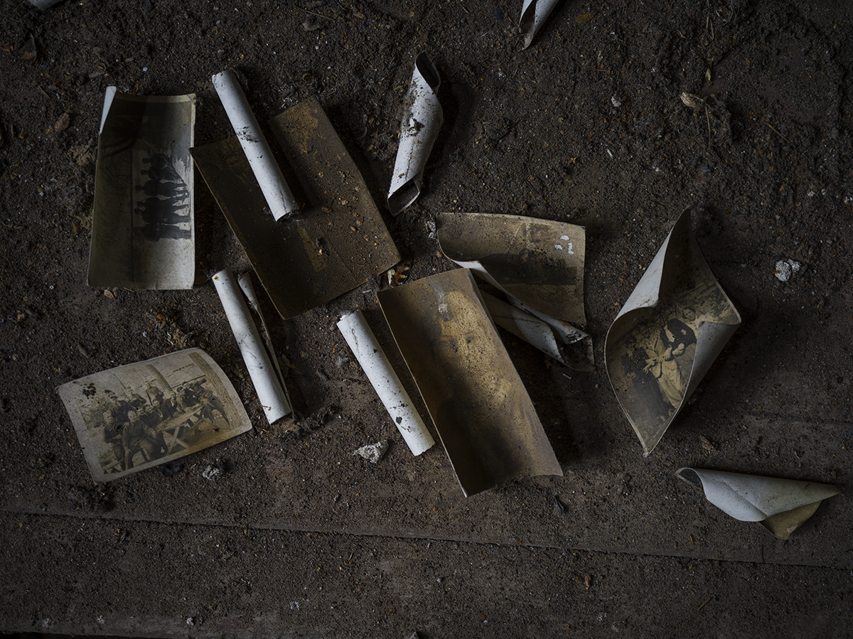 Vanhoja, käpristyneitä ja tummia valokuvia rangaistuslaitoksesta tummalla, puisella alustalla.